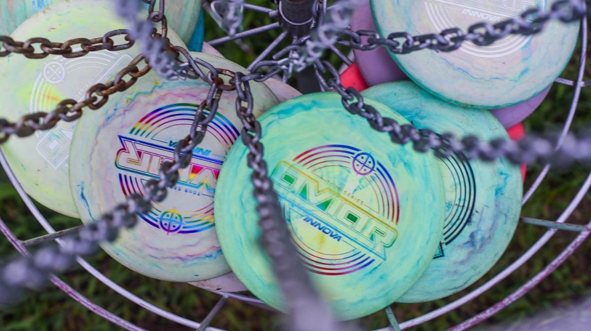 Colorful disc golf discs resting in a metal basket at a course in Lockbourne, Ohio